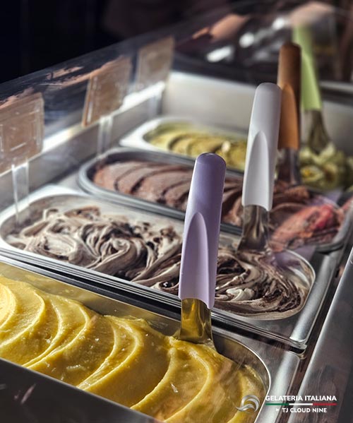 Close up of scoop handles in pans of freshly made Italian gelato